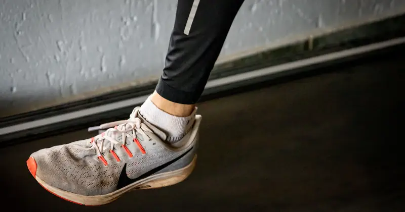 A detailed view of a sneaker mid-stride on a treadmill, showcasing active lifestyle footwear.