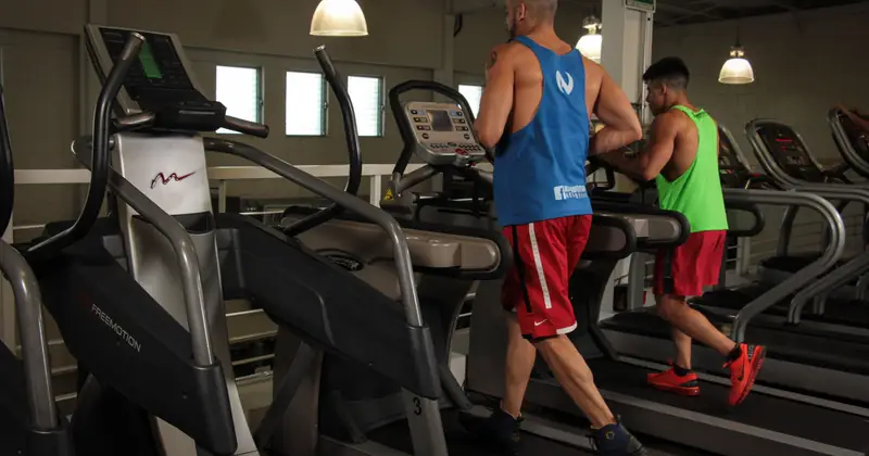Two men running on treadmills in a modern gym, promoting fitness and health.